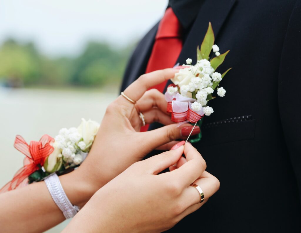 Promgoer pinning a boutonniere on her prom date